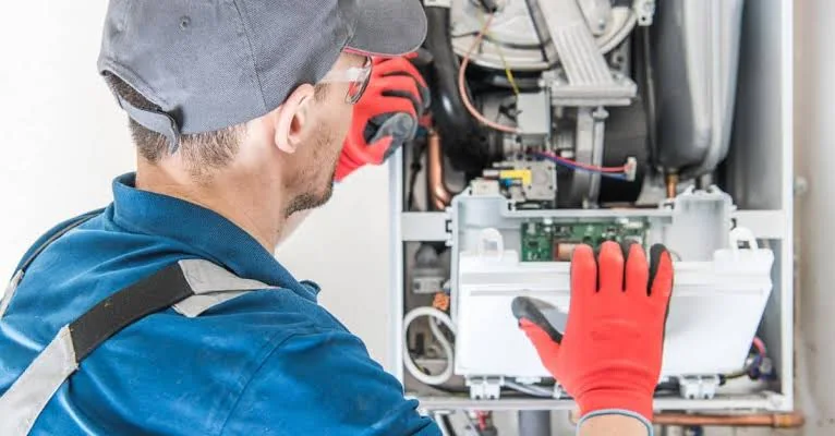 HVAC technician inspecting components inside a residential furnace