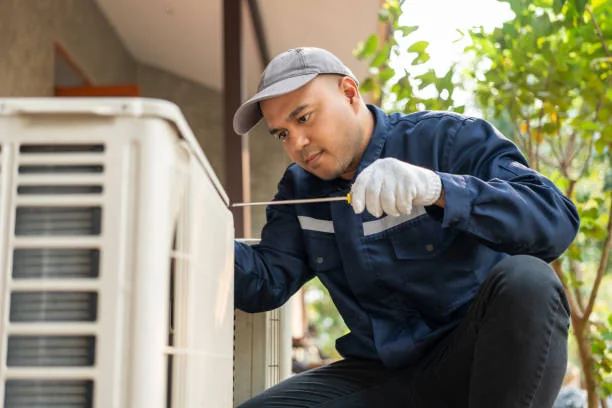 Technician inspecting an outdoor air-conditioning condenser