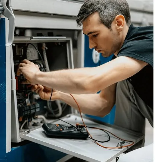 Technician testing components inside HVAC equipment with a meter
